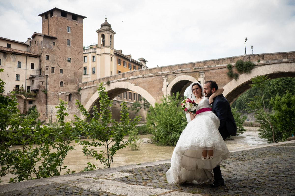 The groom lifts the bride beside the Tiber in central Rome on a spring wedding day, Silvia Cleri Photography