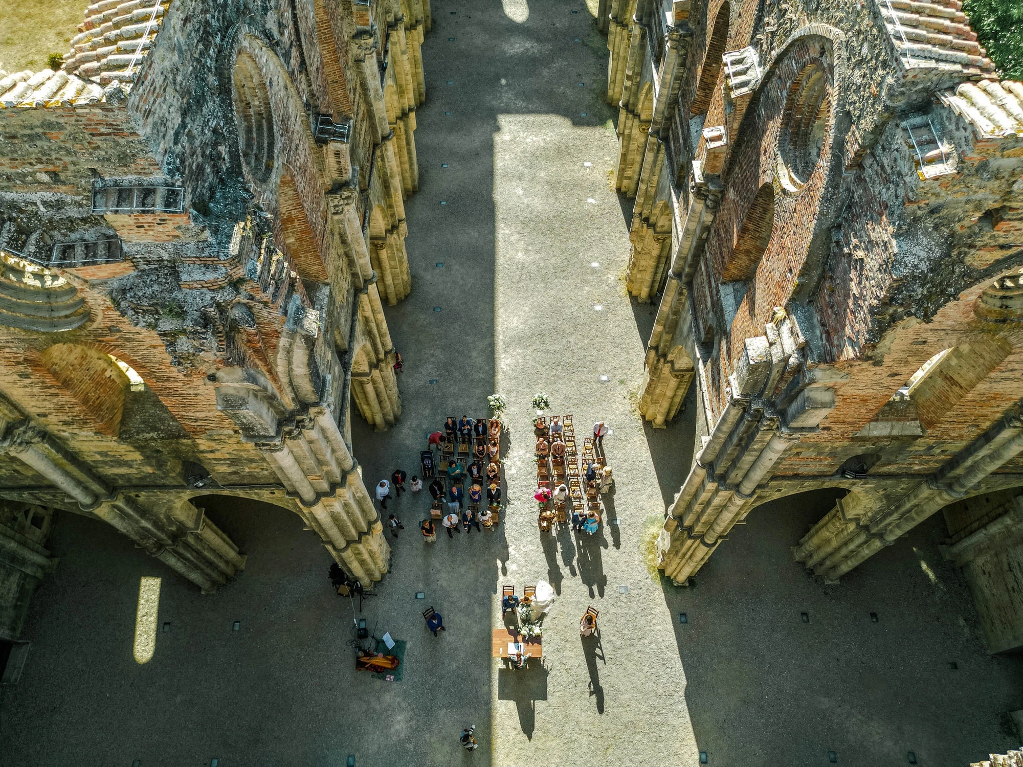 The ceremony at San Galgano seen from the air, guests seated between the open walls of the abbey, Simone Perini Photography