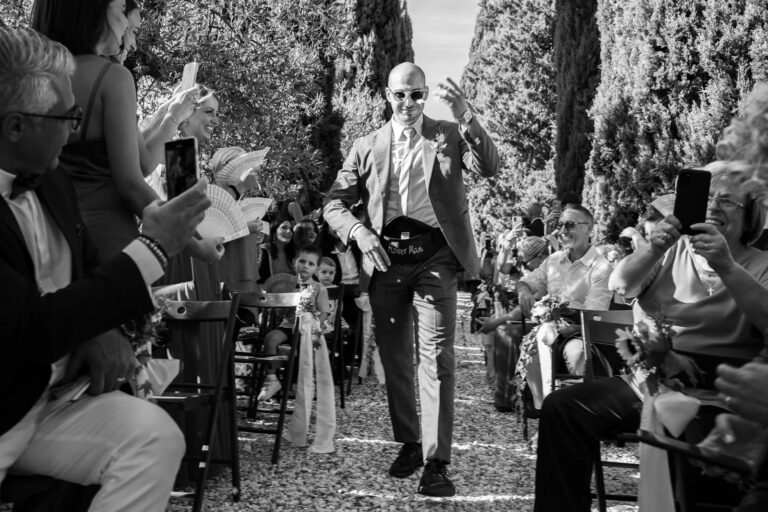 The best man plays to the crowd on his way down a cypress-lined aisle, Simone Perini Photography