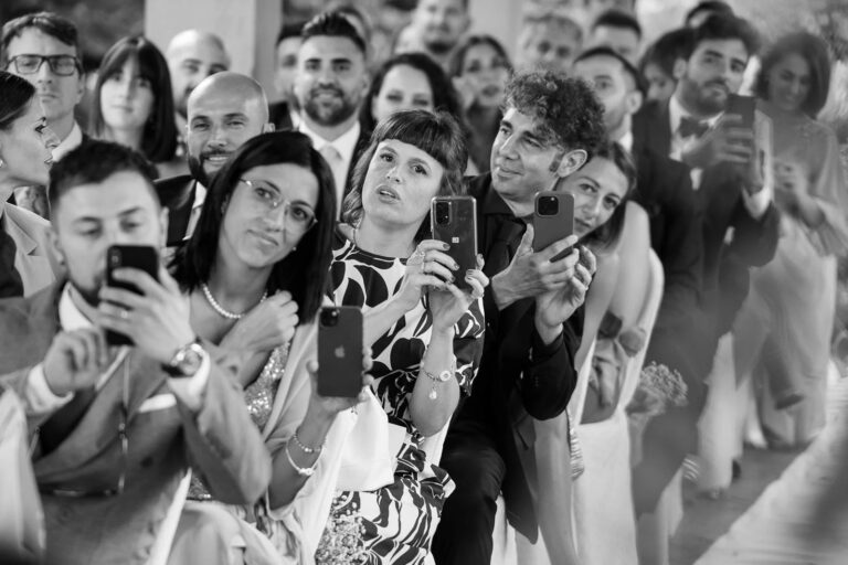 Guests reach for their phones as the ceremony begins, Simone Perini Photography