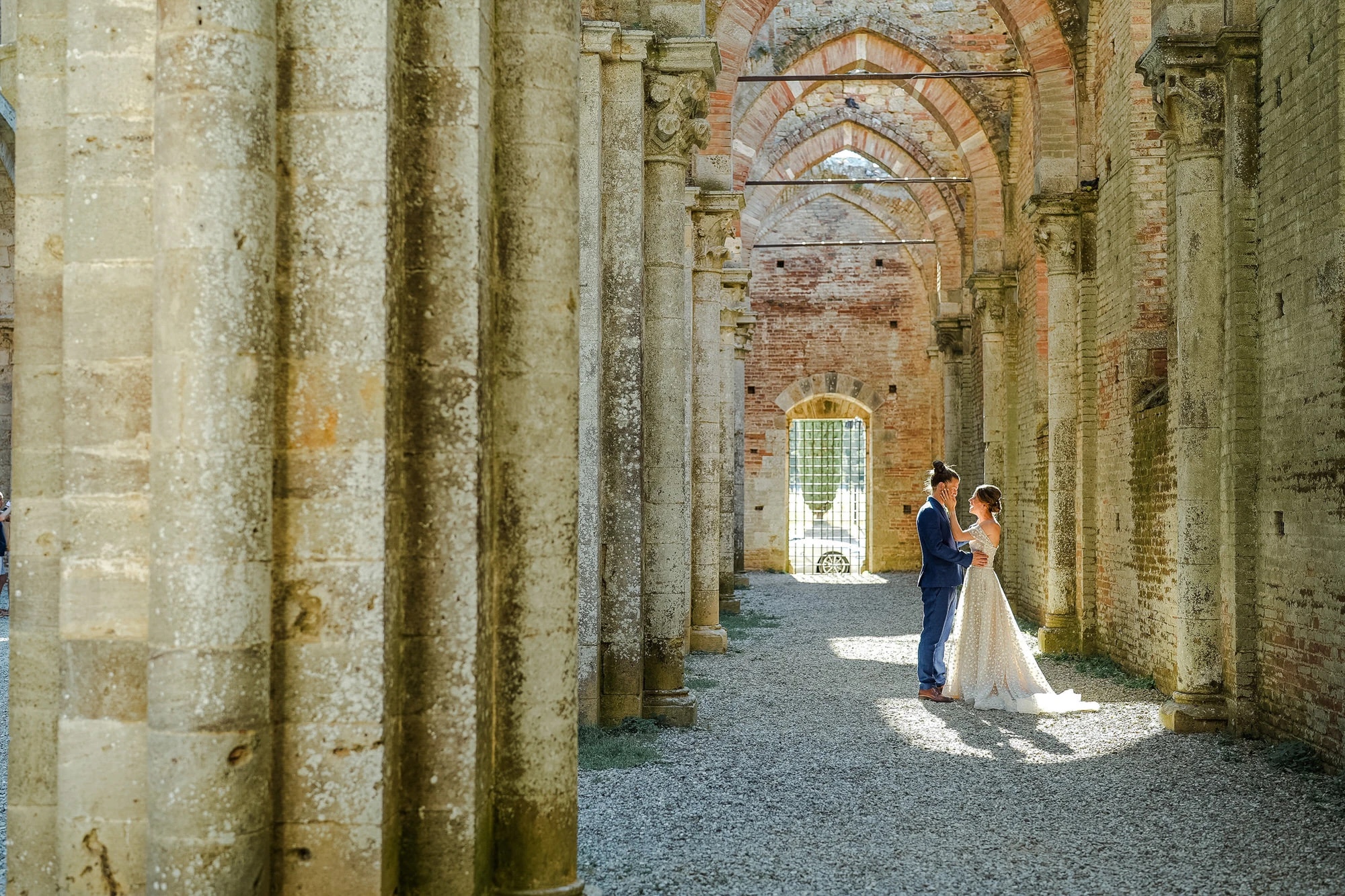 Stefano and Mariana alone in a shaft of light among the columns of San Galgano Abbey, Simone Perini Photography