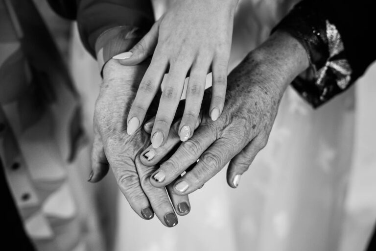 The bride's hand laid over a pair of older hands, in black and white, Simone Perini Photography