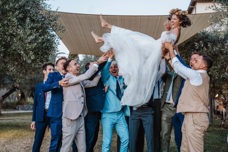 Friends throw the bride into the air under the olive trees, Simone Perini Photography