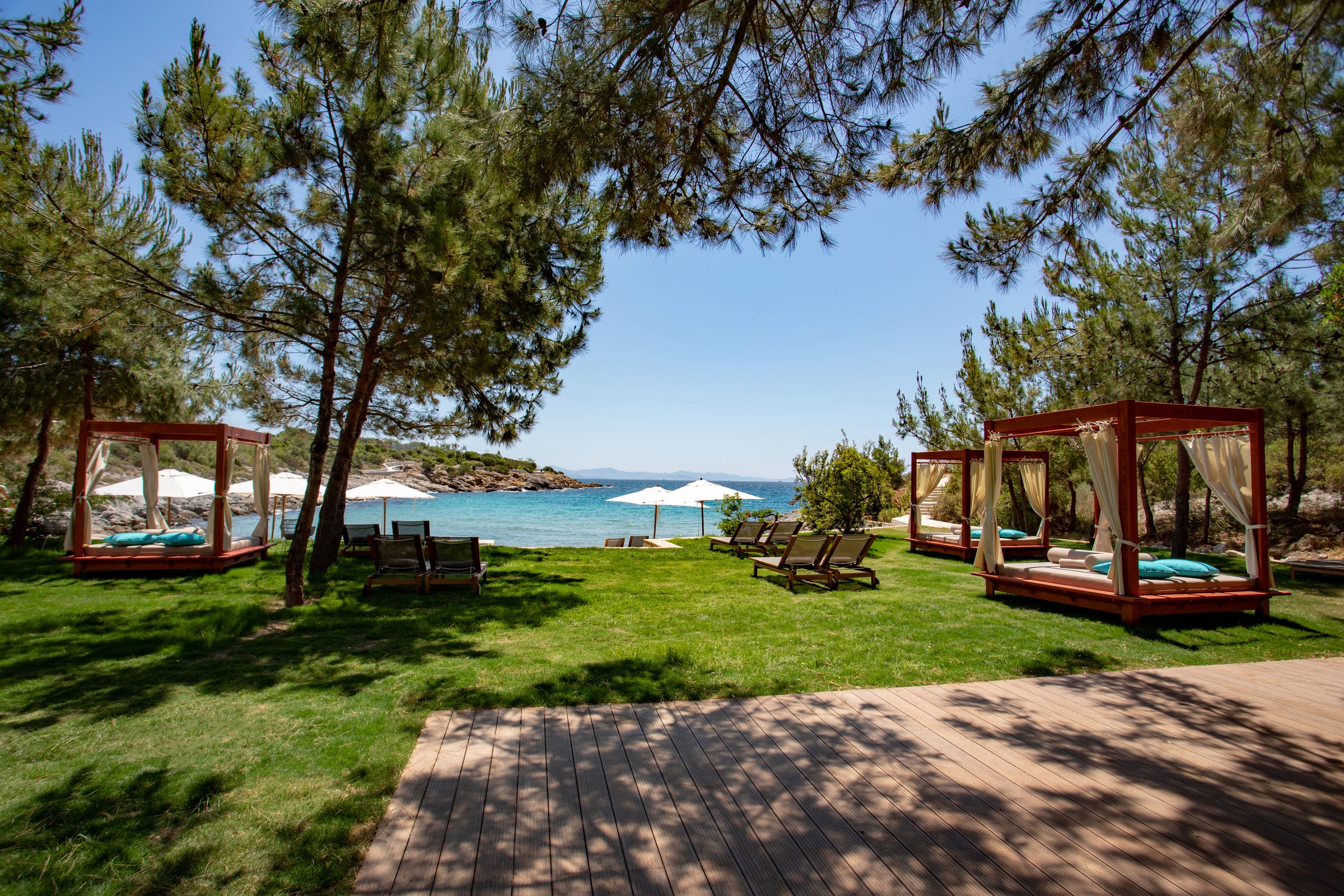 Beach cabanas and parasols under pine trees by the water, Six Senses Kaplankaya