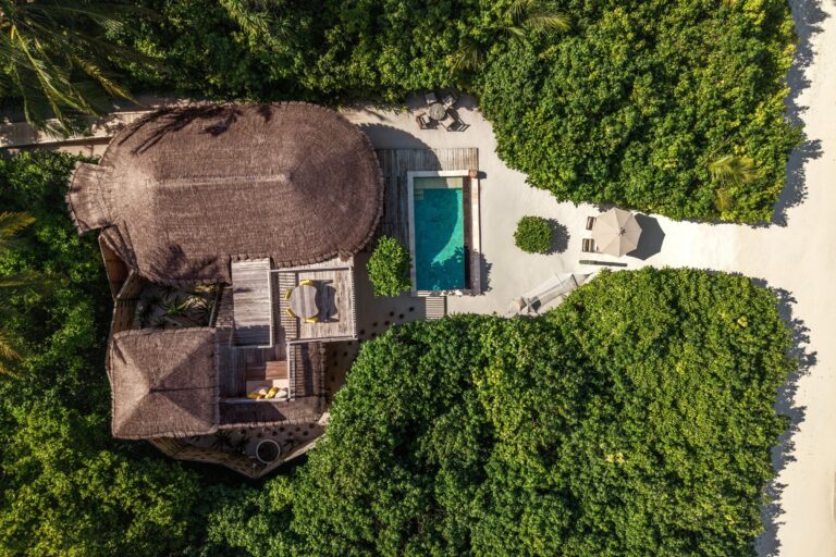 Pool and thatched-roof buildings on the white sand beach, Six Senses Laamu