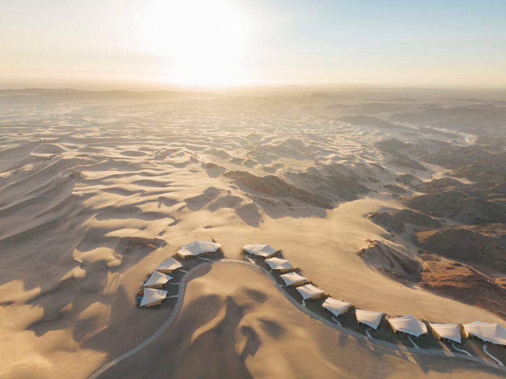 The curved line of villa roofs among the dunes, seen from the air, Six Senses Southern Dunes