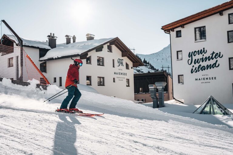 Skier passing the hotel façade, Ski Hotel Maiensee