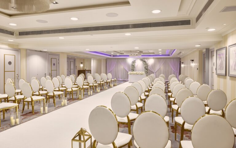 The Mayfair Suite set for a civil ceremony, with gold chairs either side of a white aisle, Sofitel London St James