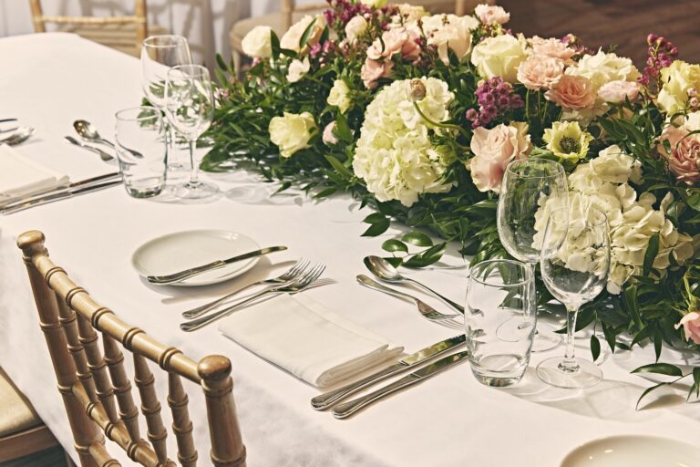Hydrangeas and roses along a wedding table laid with gold chiavari chairs, Sofitel London St James