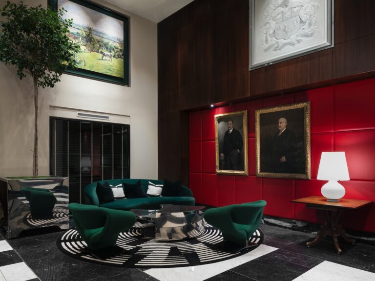 The lobby lounge with portraits on red panelling and green velvet chairs, Sofitel London St James