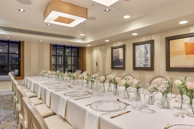A long table with glass chargers and pastel flowers for a smaller wedding dinner, Sofitel London St James