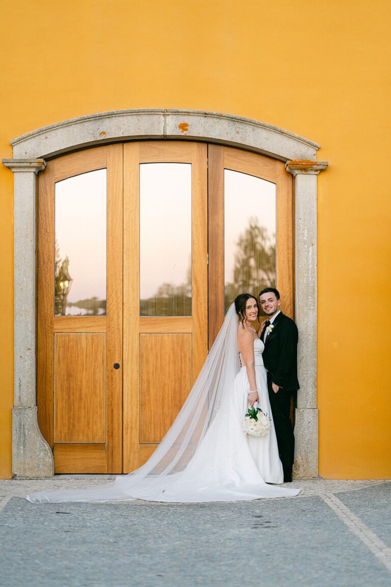 A couple standing against the wooden doors of the yellow Barn, Solar do Paço Algarve