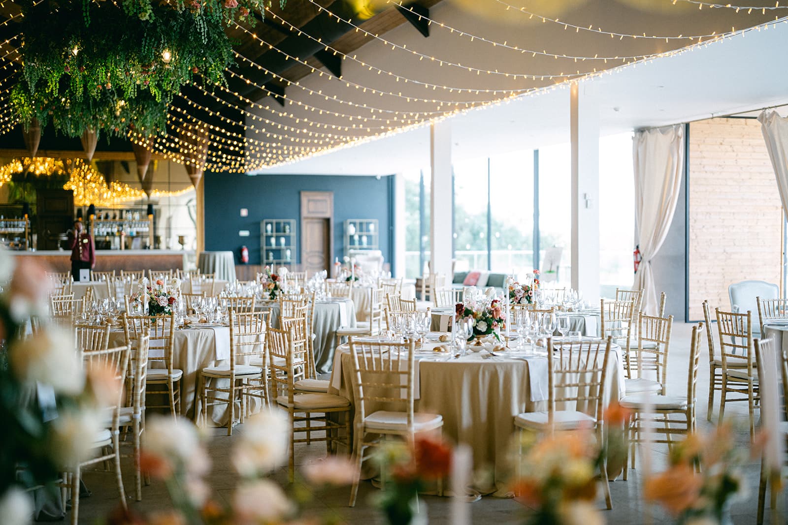 The Main Hall with laid tables, flowers in the foreground and the bar beneath fairy lights, Solar do Paço Algarve