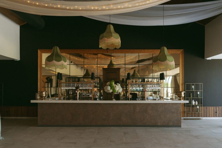 The bar in the Main Hall, with three fringed lampshades and a mirrored back wall, Solar do Paço Algarve