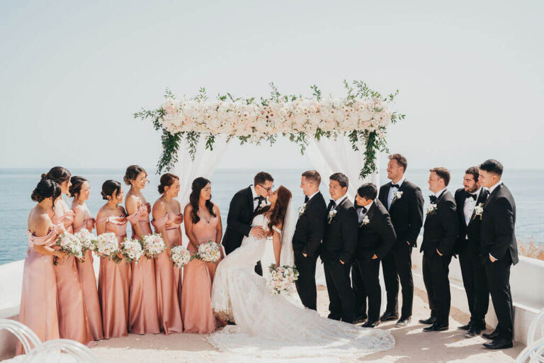 Couple and wedding party in front of a floral arch on a sea-view terrace, Sonho a Dois Algarve Wedding Planners