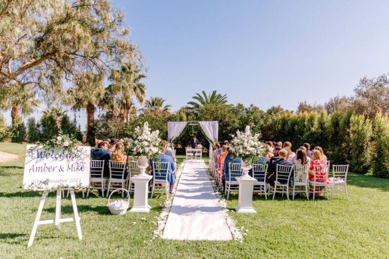 Garden ceremony with a white aisle, florals and a welcome sign among palms and olive trees, Sonho a Dois Algarve Wedding Planners