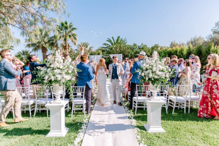 Bride walking up the aisle between white pedestals of flowers in a garden, Sonho a Dois Algarve Wedding Planners