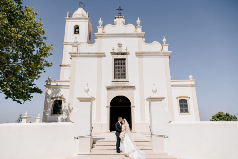 Couple on the steps of a whitewashed Algarve church, Sonho a Dois Algarve Wedding Planners