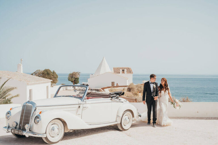 Couple beside a vintage convertible on a whitewashed coastal terrace, Sonho a Dois Algarve Wedding Planners
