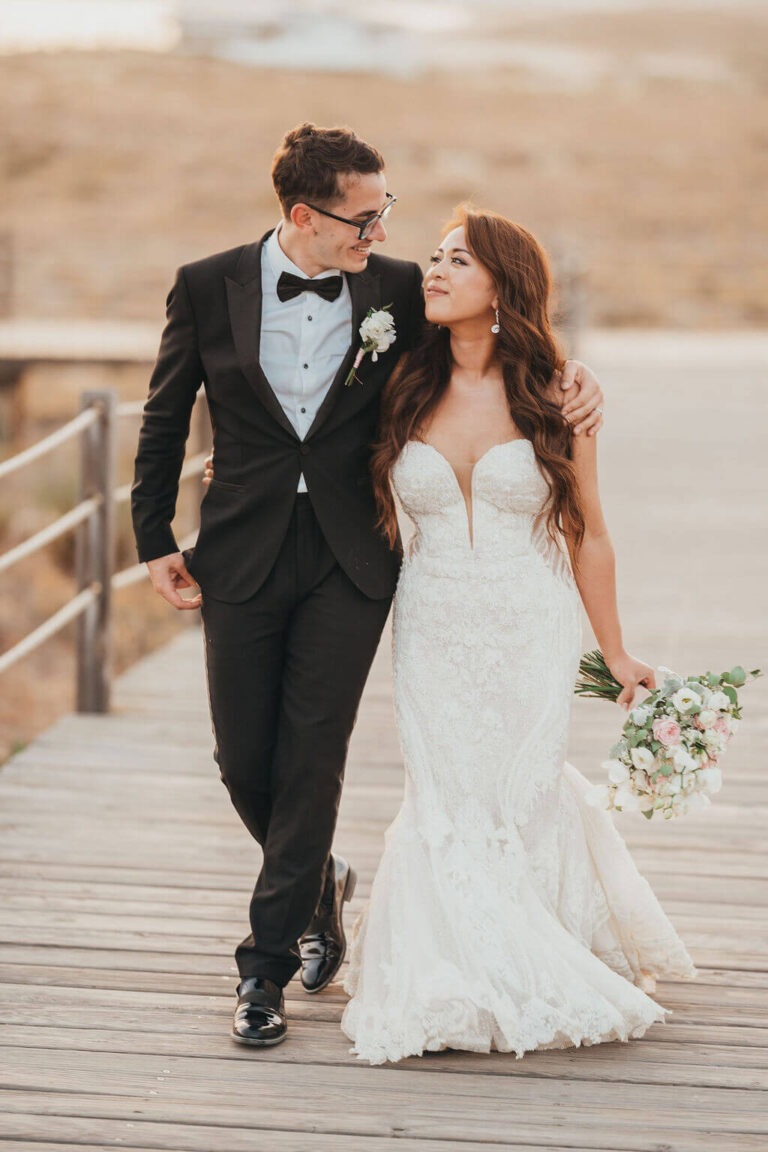 Couple walking along a wooden boardwalk at sunset, Sonho a Dois Algarve Wedding Planners