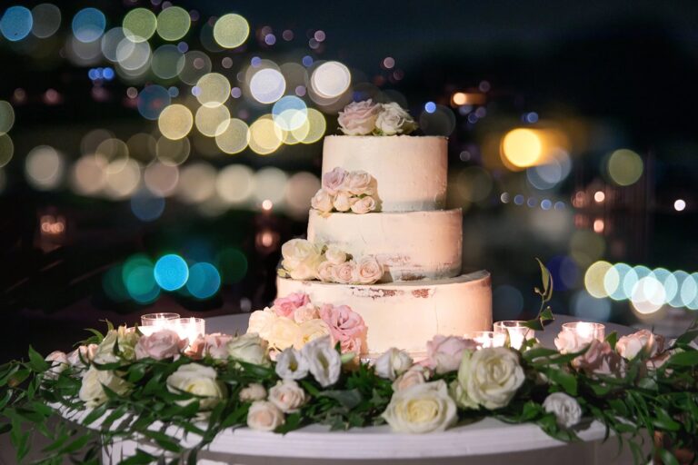 Three-tier cake with roses at an evening reception at Belmond Hotel Caruso, Ravello, Sophisticated Weddings