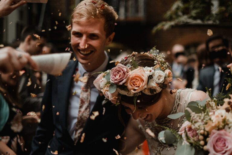 The groom, laughing in confetti, a flower crown and buttonhole, Sorcha Herbert Flowers