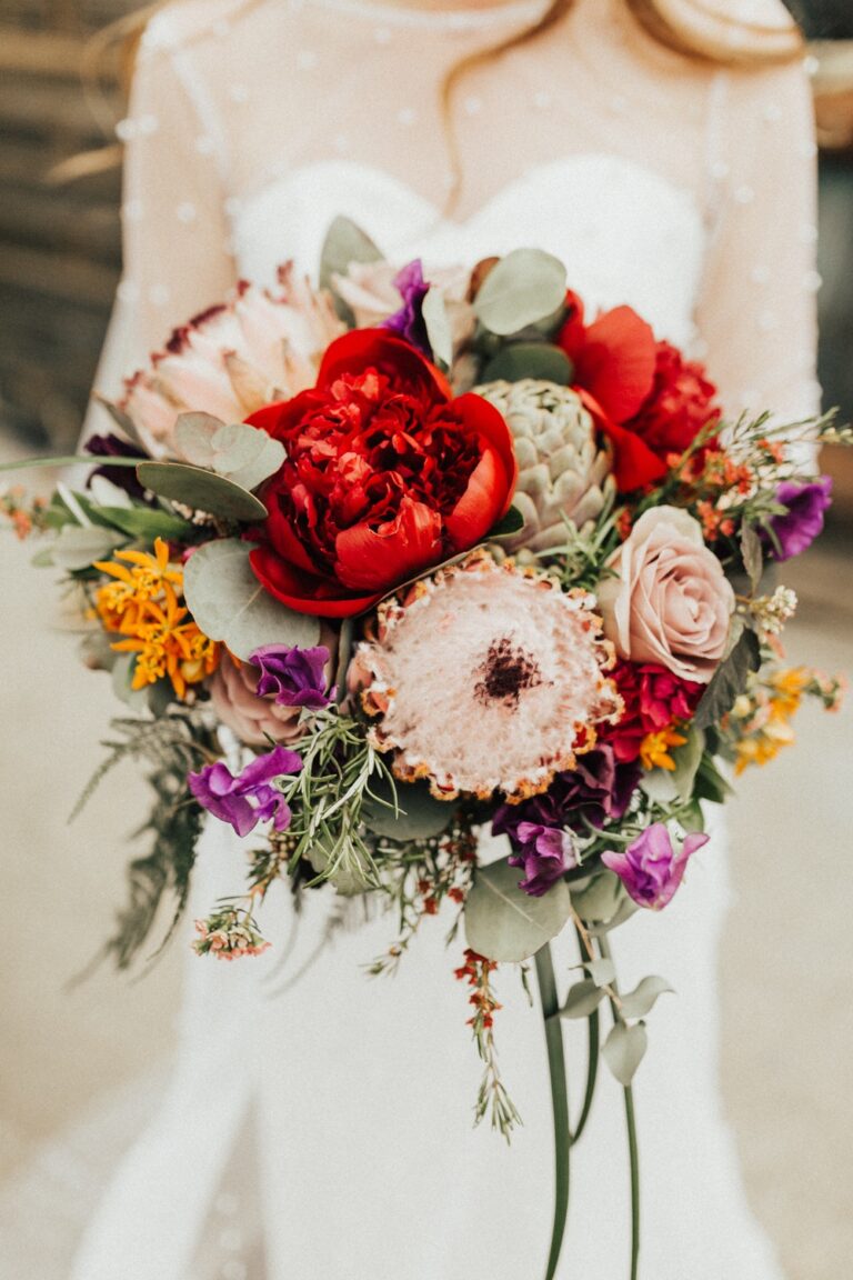 A bouquet of red rose, dahlia and marigold, held against the bodice, Sorcha Herbert Flowers