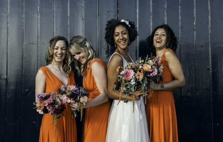 Bridesmaids in burnt orange, against a timber barn wall, Sorcha Herbert Flowers