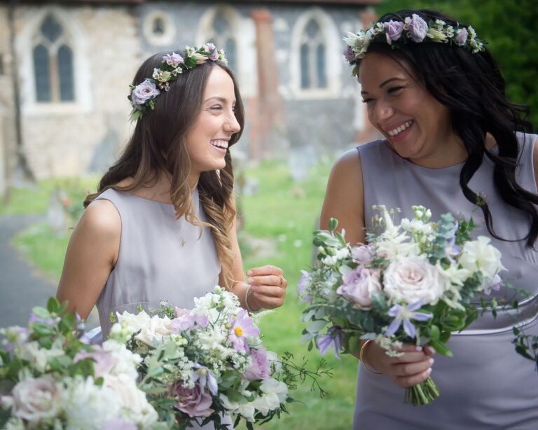 Bridesmaids laughing together, pastel bouquets, a stone church, Sorcha Herbert Flowers
