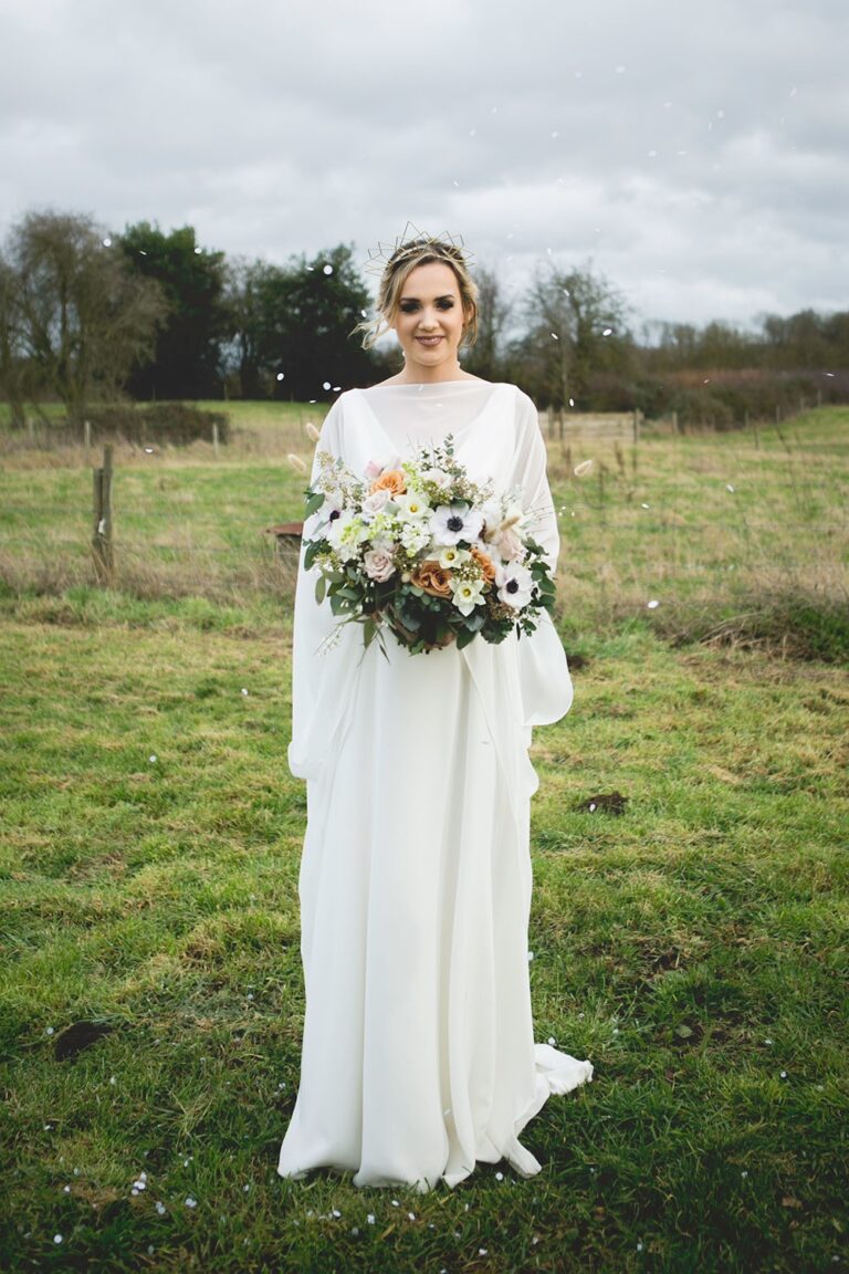 The bride alone in an open field, a loose wild bouquet, Sorcha Herbert Flowers