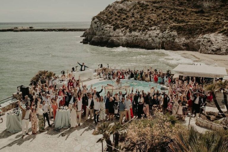 Guests gather on a cove beach, Spain4weddings