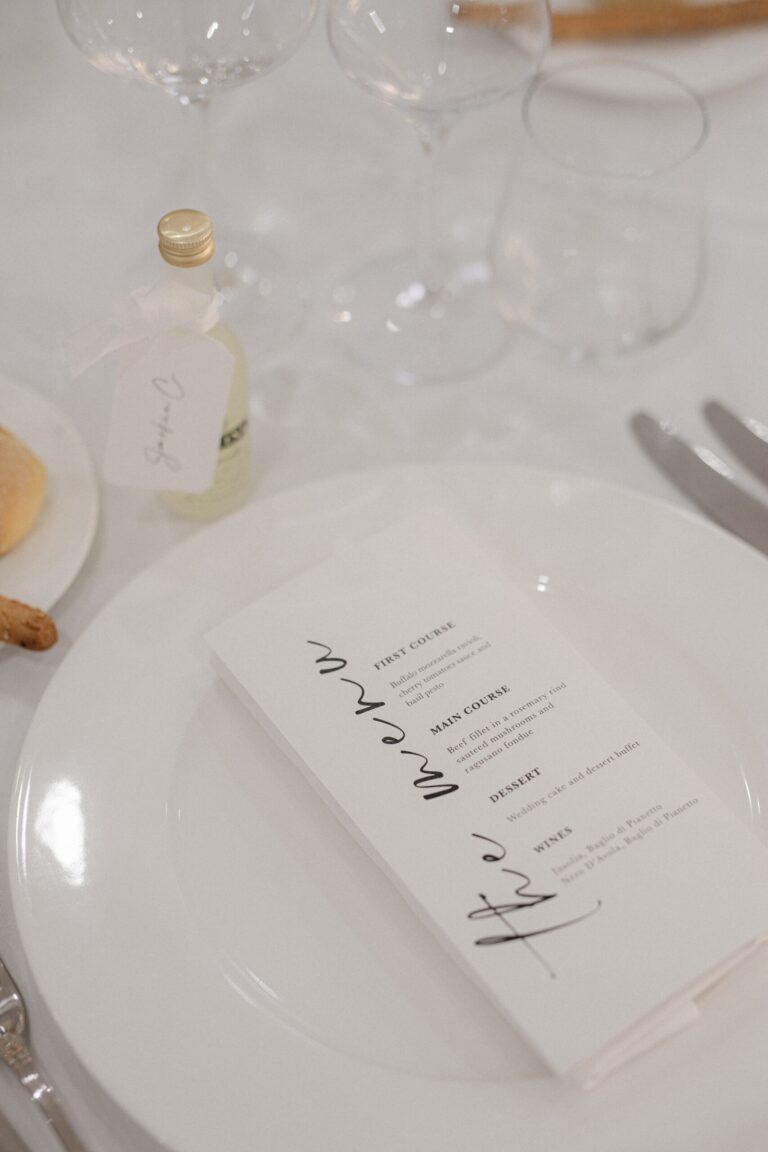 A place setting laid with a printed menu card and a favour bottle tied in ribbon, Sparx Wedding & Event Planner
