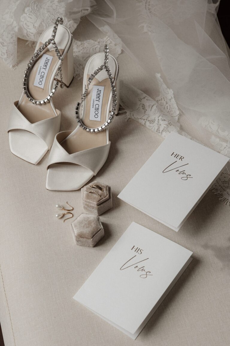 Jimmy Choo heels, vow books and pearl earrings laid out beside the bride's lace veil, Sparx Wedding & Event Planner