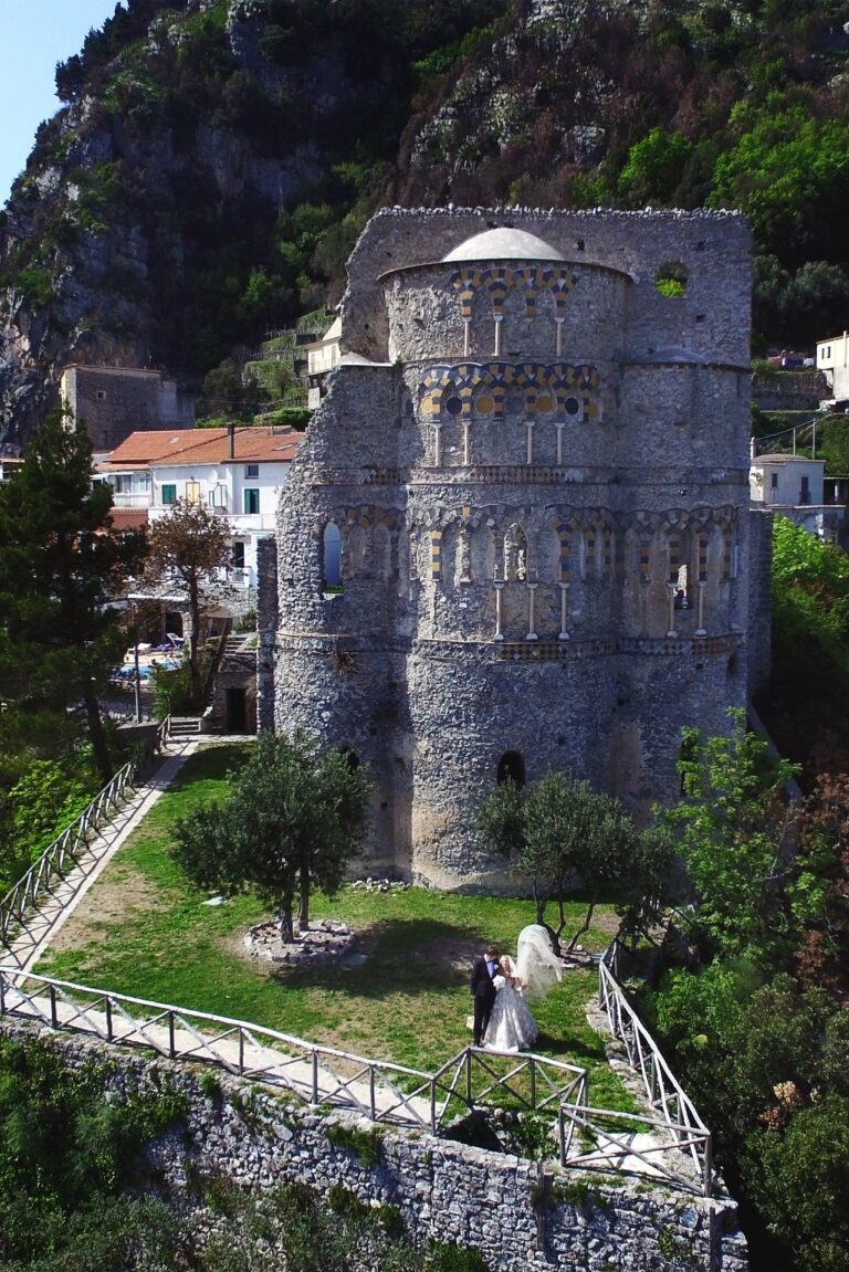 A Norman tower in an olive terrace, the couple small at the foot of it, Sposa Mediterranea By A&C