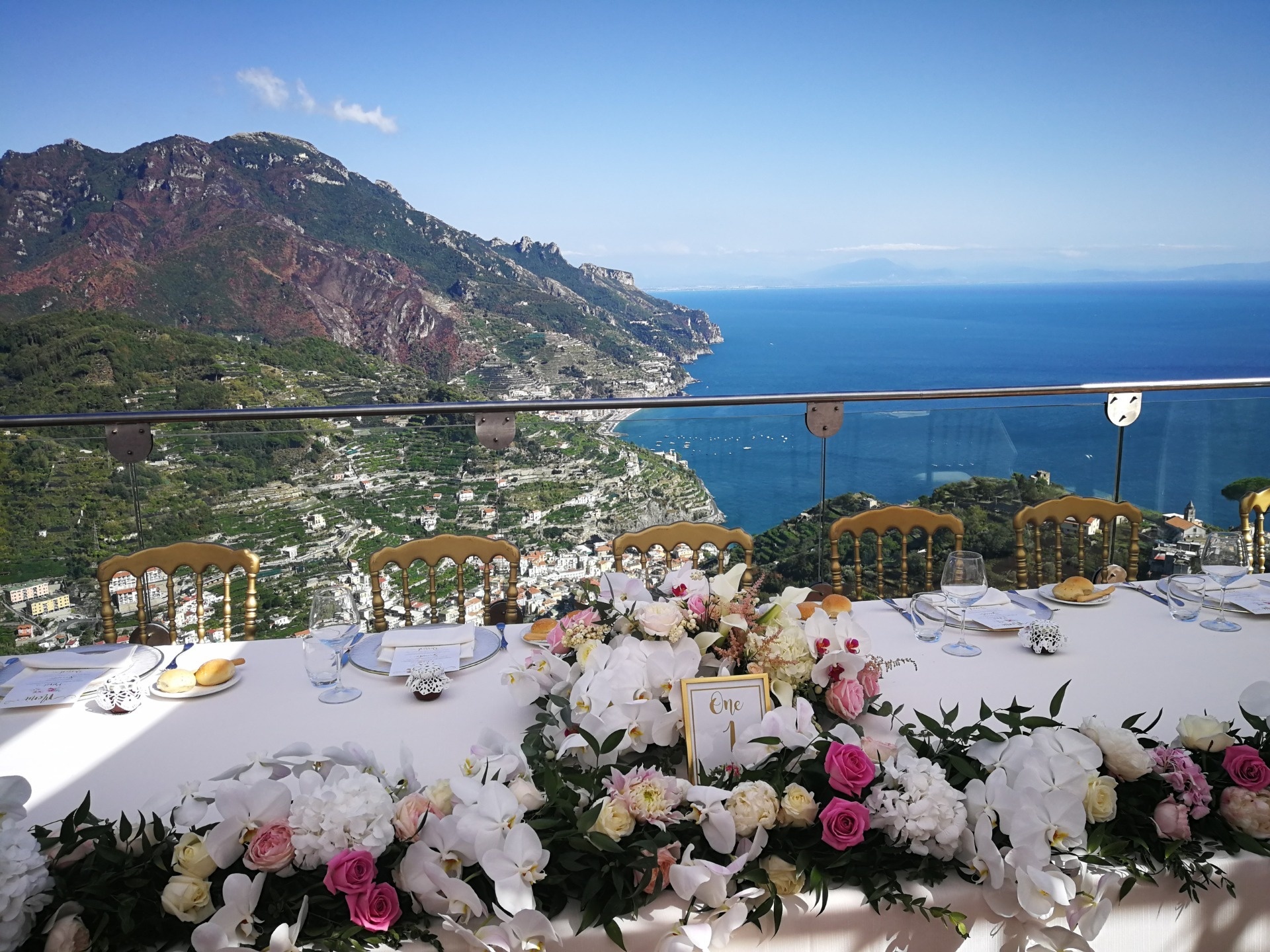 The top table on a terrace above the coast, orchids and roses along its length, Sposa Mediterranea By A&C