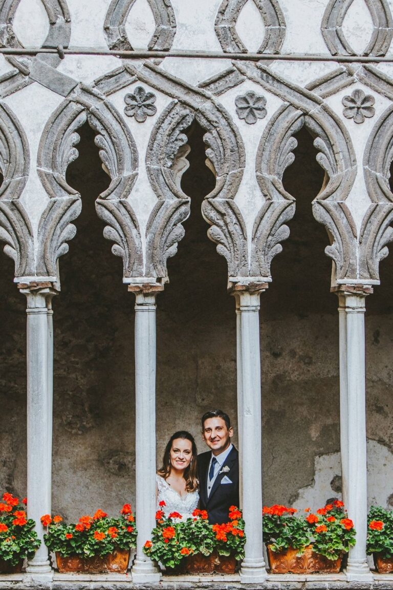 The couple framed in the arcade of a Moorish cloister, geraniums along the sill, Sposa Mediterranea By A&C