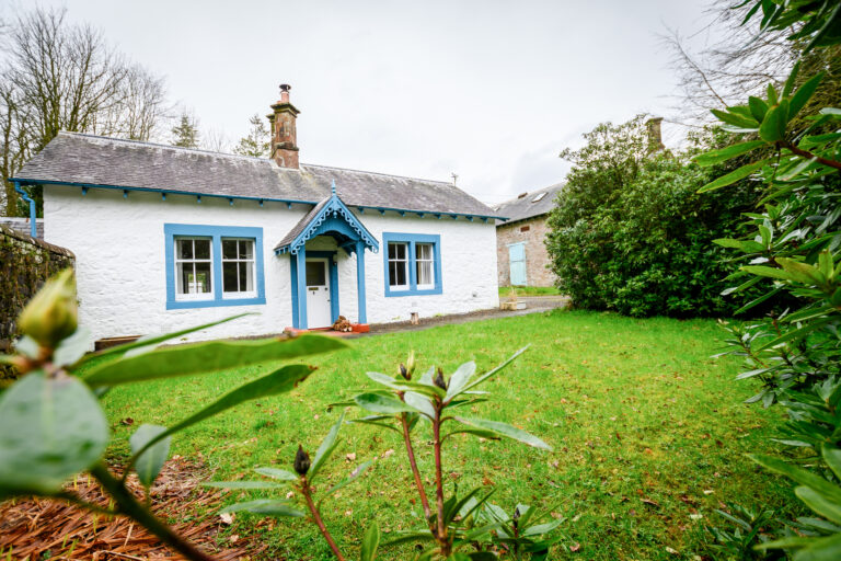 Kennel Cottage, a single-storey whitewashed cottage with its own garden in the woods, Springkell