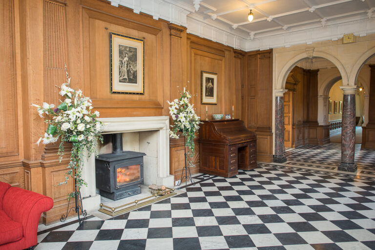 The panelled hall with its black and white marble floor, log burner and pillared arches, Springkell