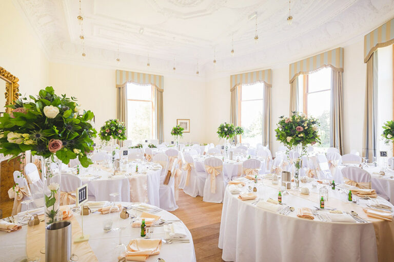 The Ballroom set with round tables, white chair covers and tall floral centrepieces, Springkell