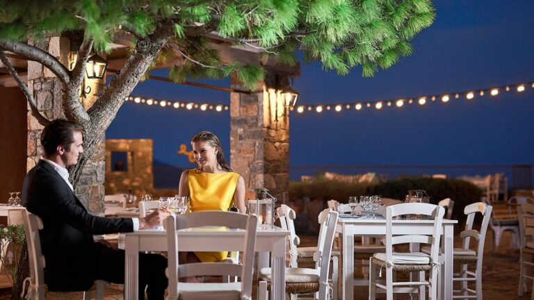 A couple dining by candlelight under the trees, St Nicolas Bay Resort Hotel and Villas