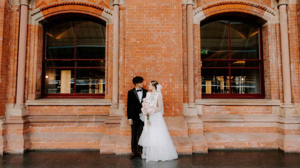 A couple beside the red brick of the hotel, St Pancras Renaissance Hotel London