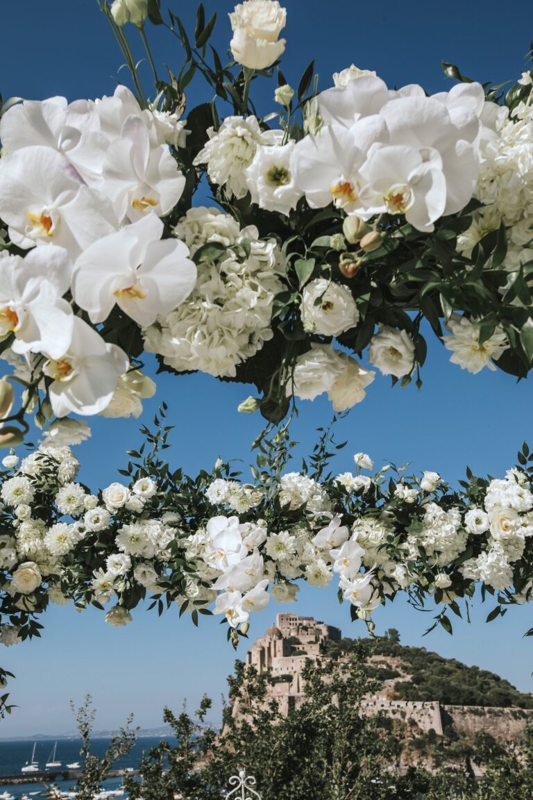 White flower arch framing the Castello Aragonese at Payton and Branden's ceremony, Ischia, Stefania Silvestro