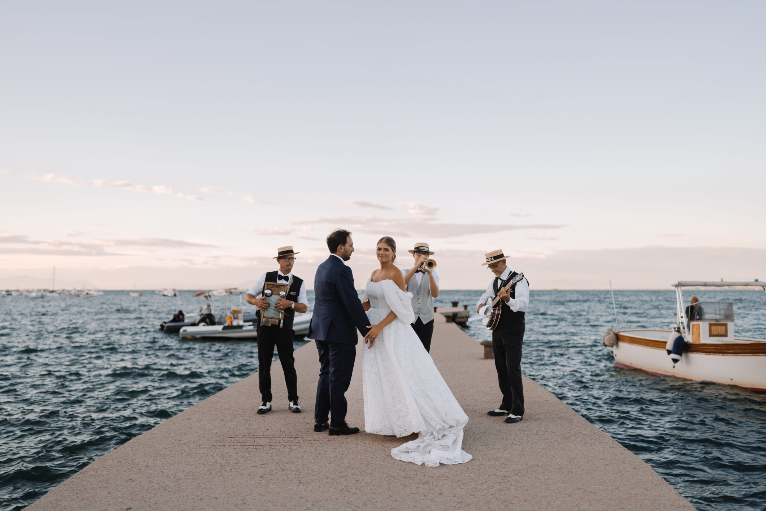 Jolanda and Danilo with musicians on the jetty before travelling to their reception by wooden boat, Ischia, Stefania Silvestro