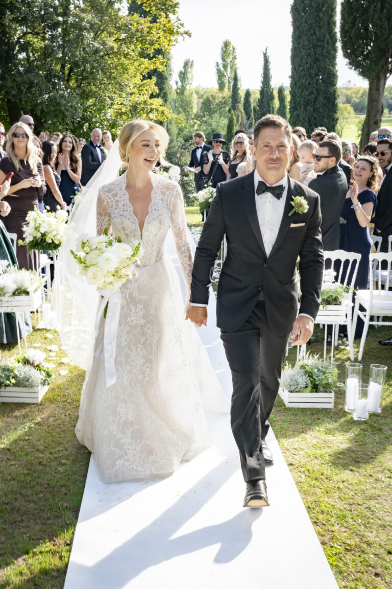 The newlyweds walking back down a white aisle through their guests in a garden ceremony, Stefano Lunardi