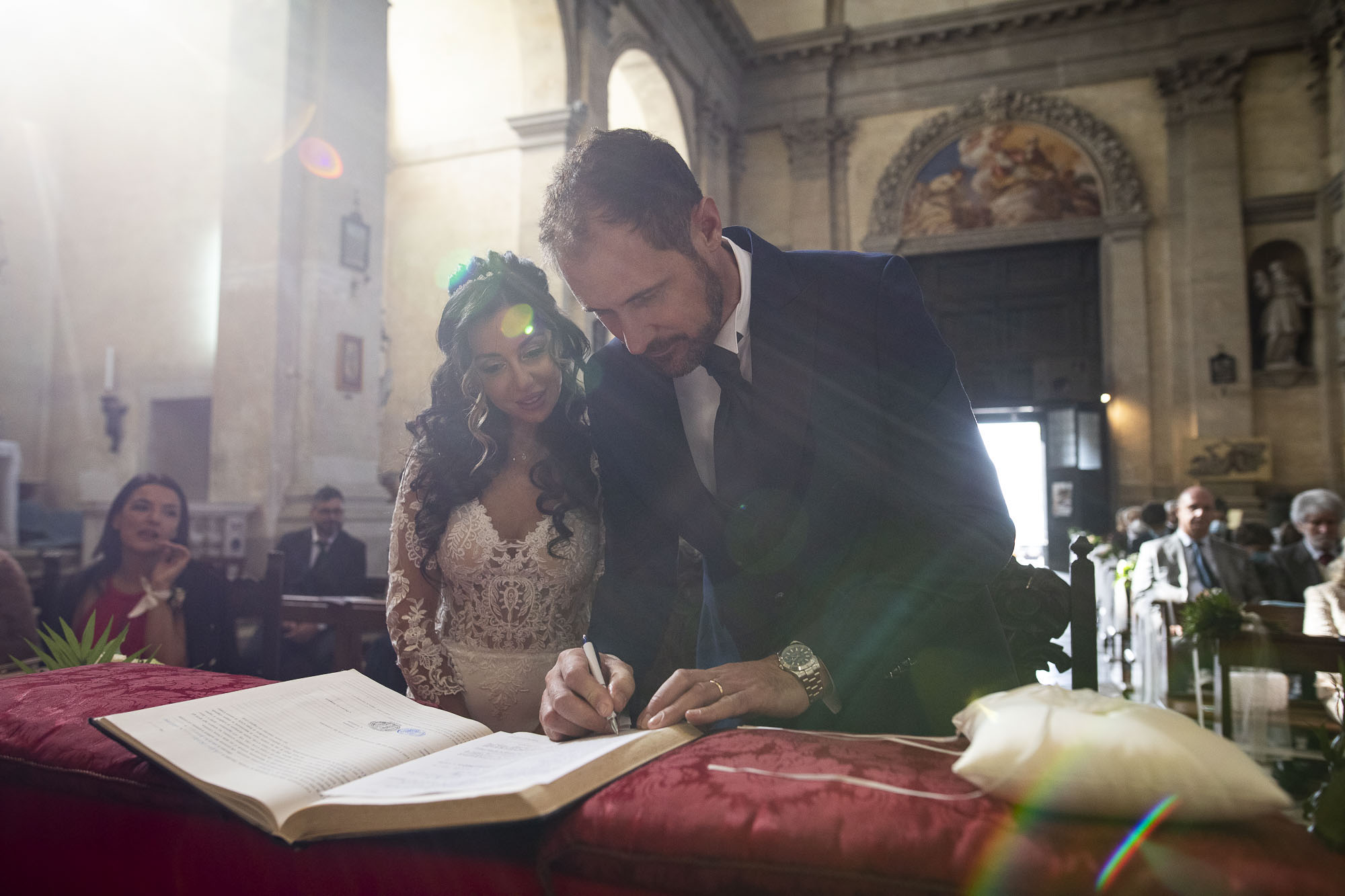 Signing the register at a church wedding, light flaring across the altar, Stefano Lunardi