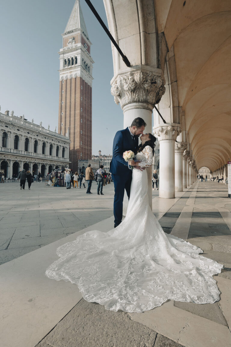 A couple by the arcades of St Mark's Square in Venice, the campanile behind them, Stefano Lunardi