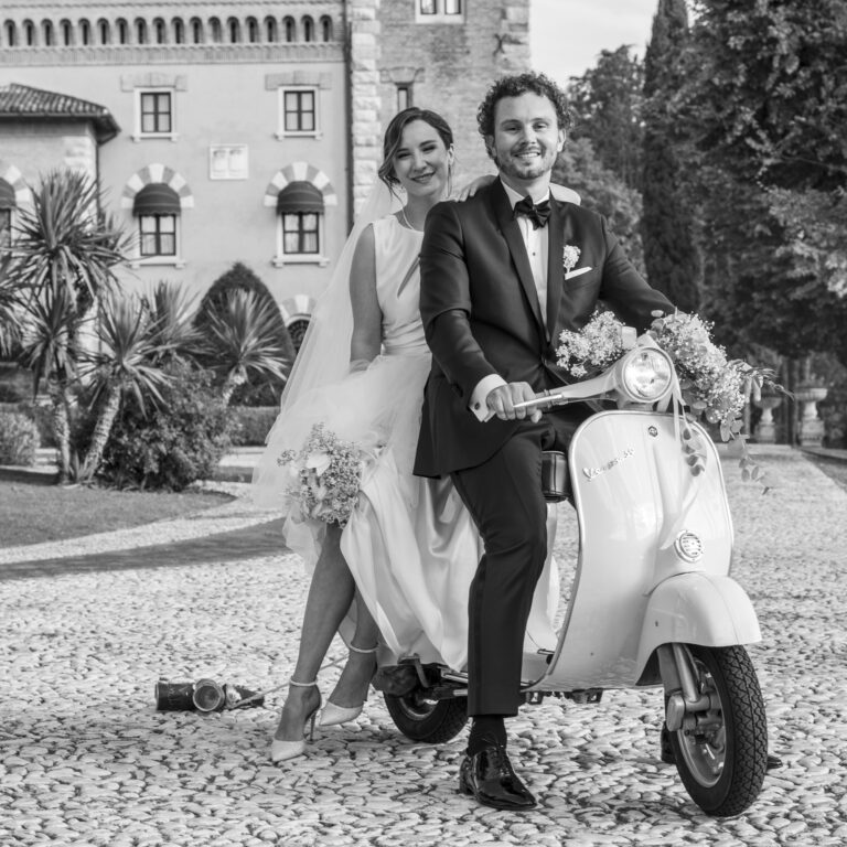 Bride and groom on a vintage Vespa in a castle courtyard, in black and white, Stefano Lunardi