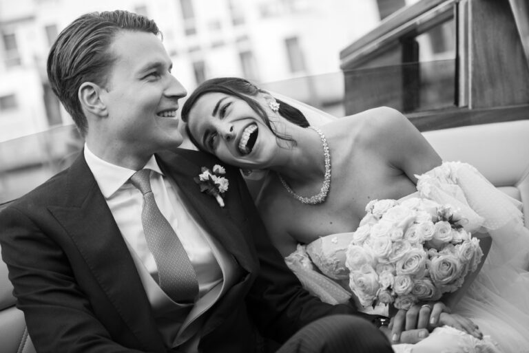 A bride laughing on her husband's shoulder after their wedding in Venice, in black and white, Stefano Lunardi
