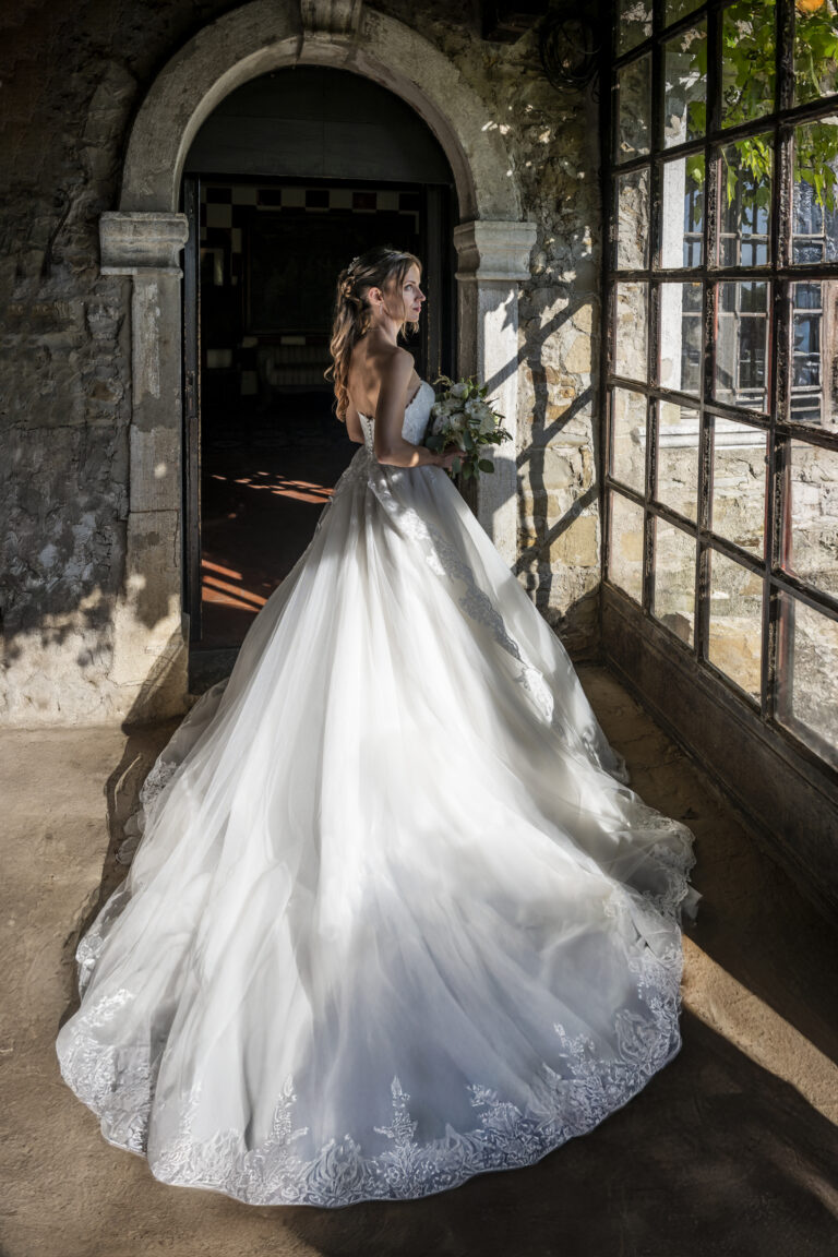 The bride and her full train in the light of a stone arcade, Stefano Lunardi
