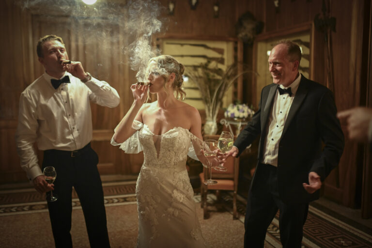 The bride and two guests sharing cigars and laughter in a wood-panelled room, Stefano Lunardi